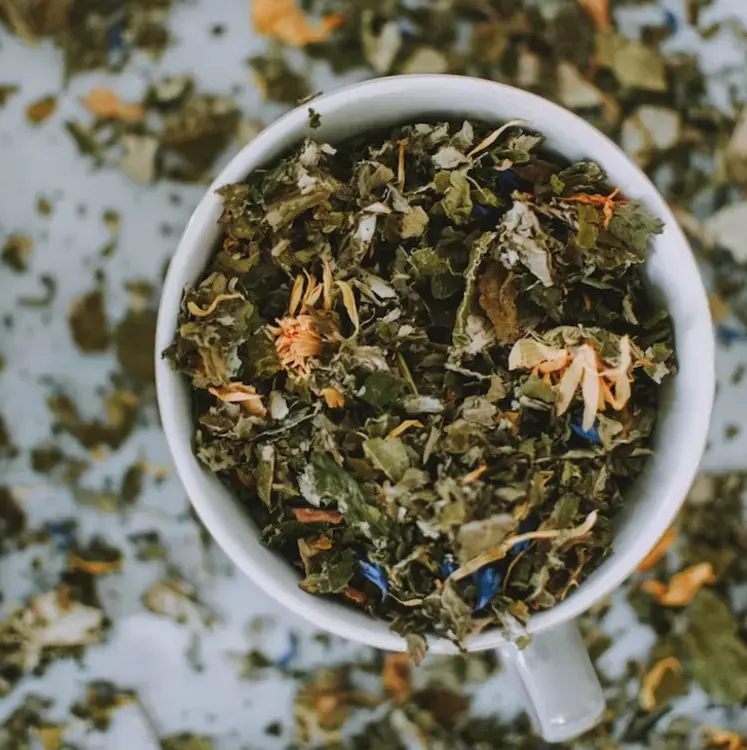 dried herbal tea leaves in white mug on white table