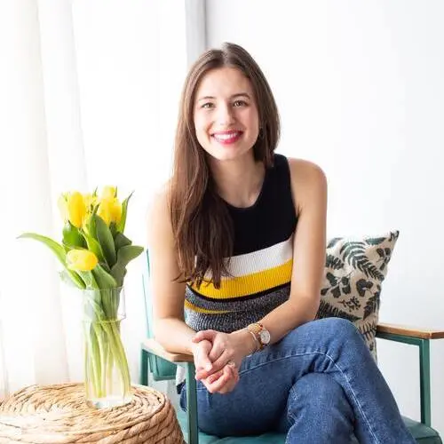 dr. emily rotella naturopathic doctor headshot on chair against natural lighting windows with tulips in vase cropped