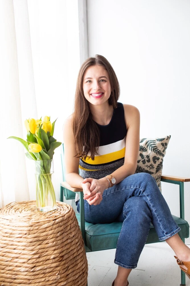 dr. emily rotella naturopathic doctor headshot on chair against natural lighting windows with tulips in vase