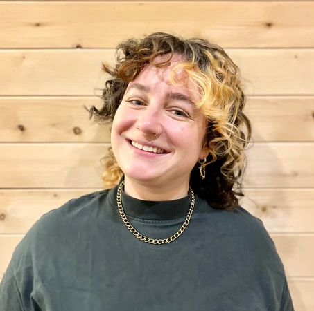 melanie udell acupuncturist headshot against wooden panel wall wearing green shirt at roncys apothecary and clinic cropped