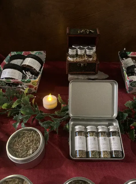 herbal apothecary kit and sample tea tins on a holiday tablet set-up with maroon table cloth